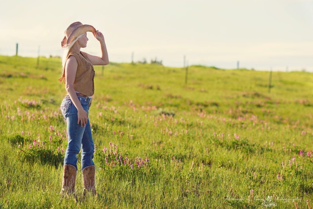 A country woman, a farmer standing on a huge green grassed farm land starring at the sky
